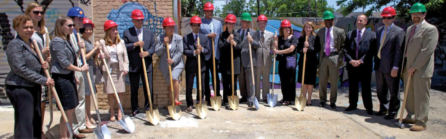 Image of team holding shovels and in hardhats 