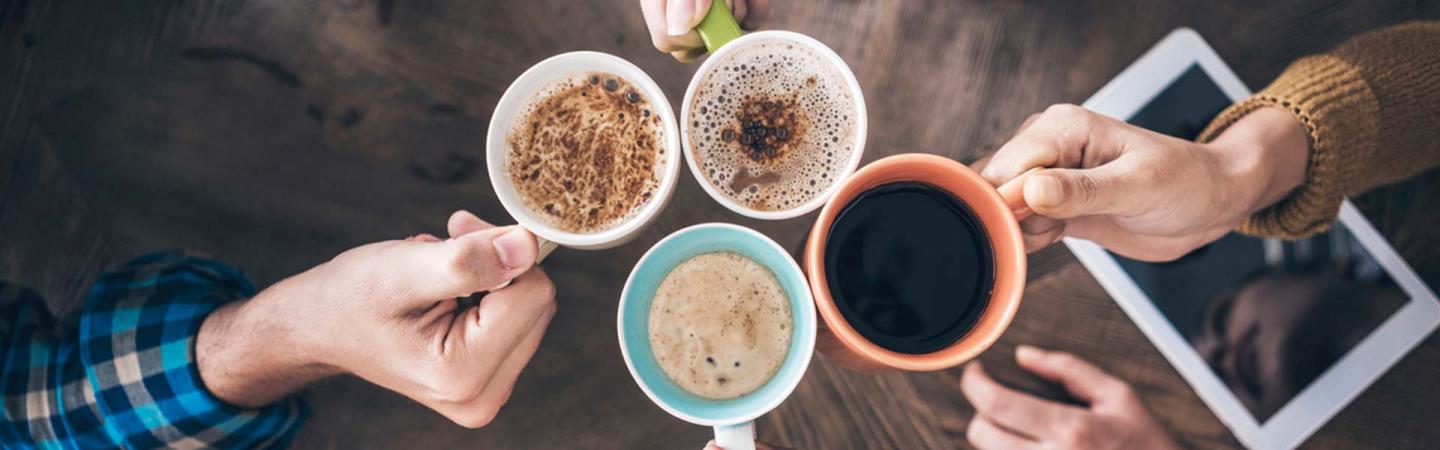 A photo of several coffee cups being held by people who are toasting