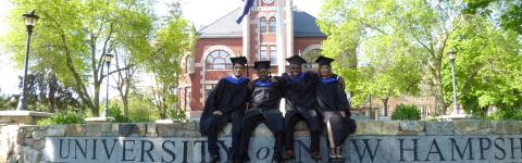 Recent graduates posing in front of Thompson Hall.