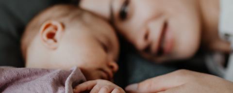 mother holding hand of sleeping baby