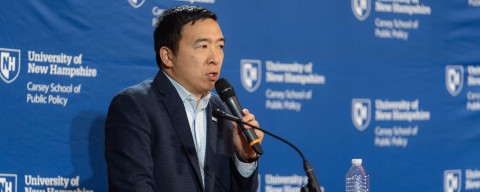 Andrew Yang speaking at a University of New Hampshire podium