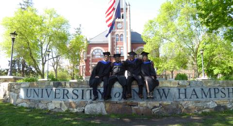 Recent graduates posing in front of Thompson Hall.
