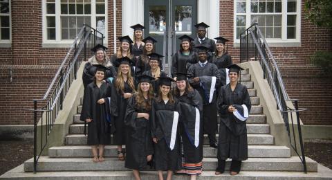 Recent graduates posing on the steps of Huddleston Hall.