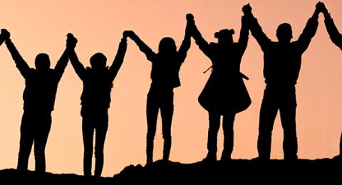 Peace Corps volunteers holding hands, silhouetted against the sunset.