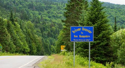 New Hampshire road and mountains with welcome to new hampshire sign