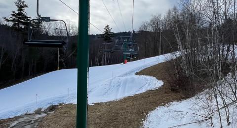 New hampshire ski area in winter with patches of exposed ground alongside snow covered trails and chair lift. Photo by Maddie Smith. 