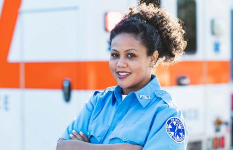 A photo of a first responder emergency technician standing in front of an ambulance