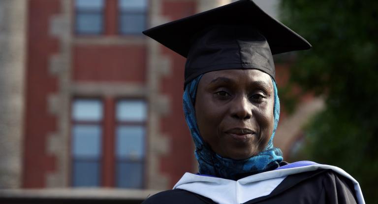 Safiya Adamu stands in her graduation cap in front of Carsey