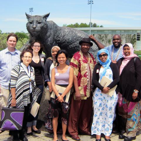 Carsey alumni standing in front of the Wild E. Cat statue at UNH