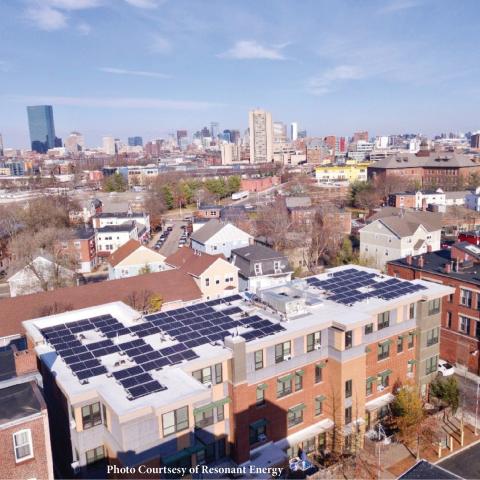 A photo showing solar panels set atop a house with a city in the background