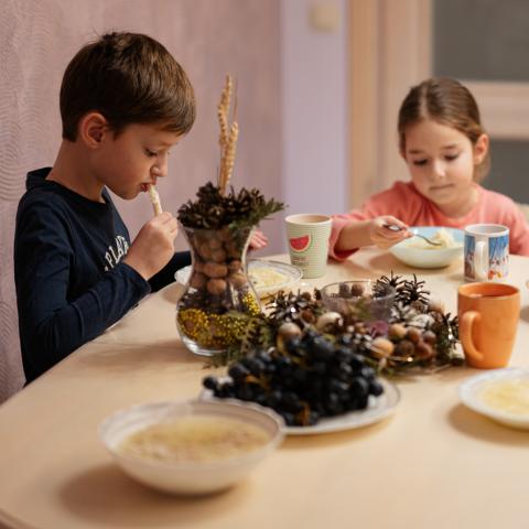 a boy and girl eating a meal at kitchen table