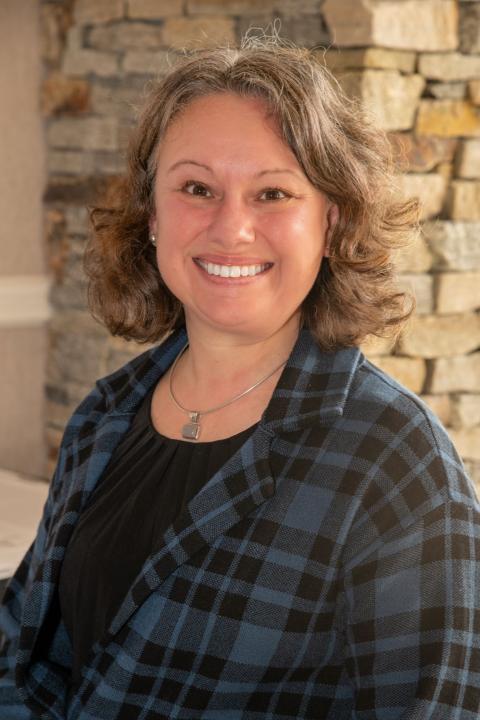 image of rebecca ross standing in front of a brick wall 