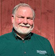 Shawn Jasper in front of wood background with green shirt.