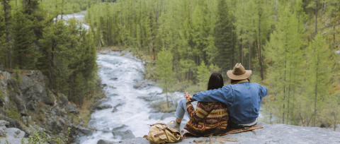 couple sitting on rock overlooking nh river and mountains