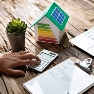 financial papers on a desk with a model of a green house