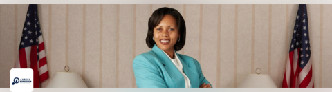 female politician standing alongside two american flags