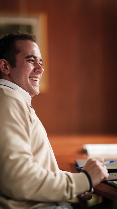 community development masters student sitting at a table smiling, shot from the right side