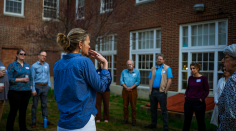 Group of people standing in a circle outside a building talking